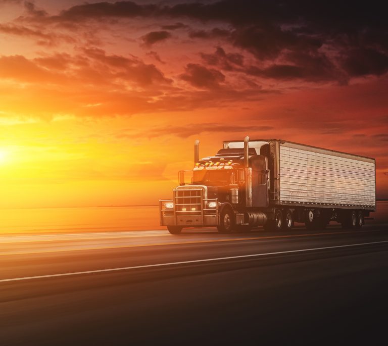 A large truck drives on an open highway at sunset, with dramatic orange and red skies in the background, much like the powerful drive of Dayton criminal defense lawyers who navigate complex legal roads with determination.
